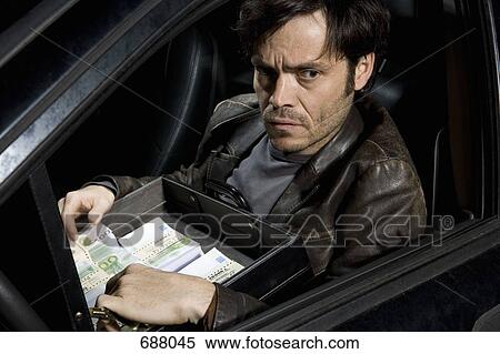 A man sitting in a car with an open briefcase full of money View Large Photo Image Stock Photography - A man sitting in a car with an open briefcase full of money. Fotosearch