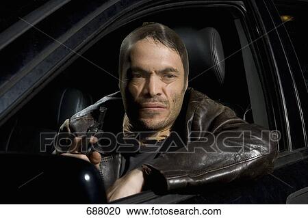 A man with a nylon over his face sitting in a car holding a gun View Large Photo Image Stock Image - A man with a nylon over his face sitting in a car holding a gun. Fotosearch