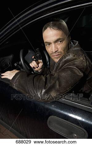 A man with a nylon over his face sitting in a car holding a gun View Large Photo Image Stock Photo - A man with a nylon over his face sitting in a car holding a gun. Fotosearch
