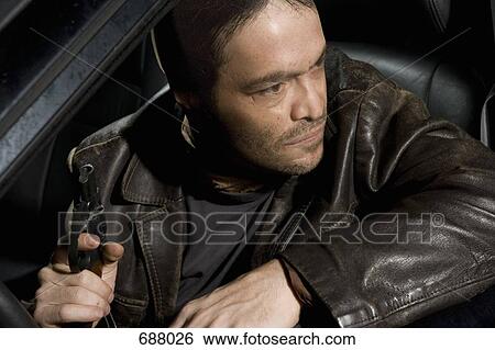 A man with a nylon over his face sitting in a car holding a gun View Large Photo Image Stock Photograph - A man with a nylon over his face sitting in a car holding a gun. Fotosearch