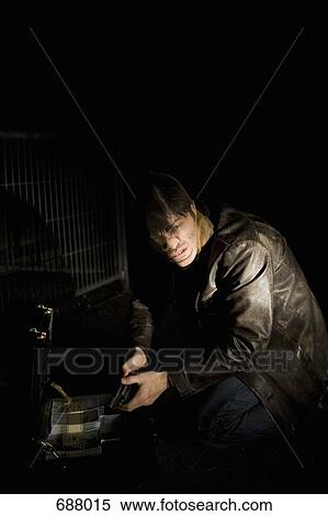 A man with a nylon over his face holding a gun with a briefcase full of money View Large Photo Image Stock Photography - A man with a nylon over his face holding a gun with a briefcase full of money. Fotosearch