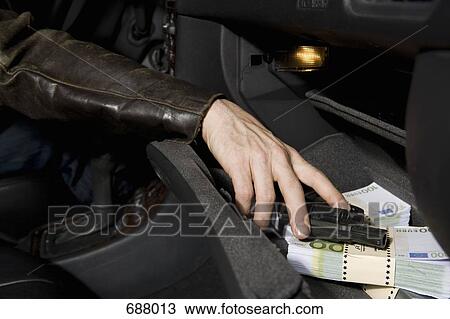 A man's hand grabbing a gun from a glove compartment full of European Union currency View Large Photo Image Stock Image - A man's hand grabbing a gun from a glove compartment full of European Union currency. Fotosearch