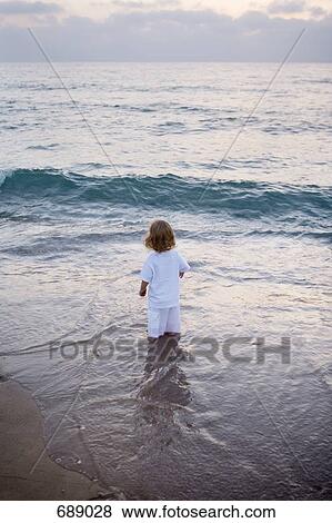 A child standing in the surf on a beach View Large Photo Image Stock Photo - A child standing in the surf on a beach. Fotosearch