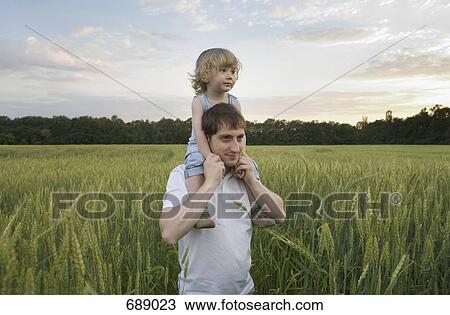 Stock Image - A man carrying a child on his shoulders. Fotosearch