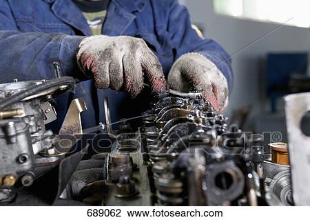 A mechanic fixing an engine View Large Photo Image Stock Image - A mechanic fixing an engine. Fotosearch