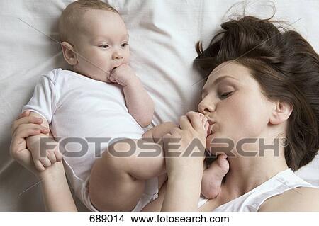 Picture - A mother kissing her baby's foot. Fotosearch