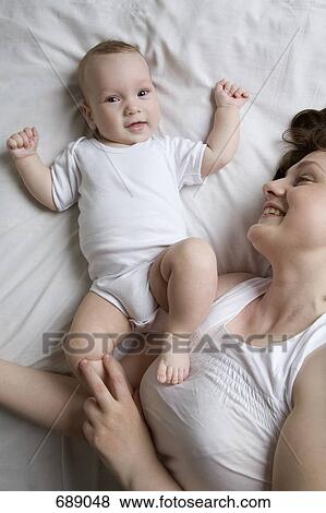 A mother lying on a bed with a baby View Large Photo Image Stock Photo - A mother lying on a bed with a baby. Fotosearch