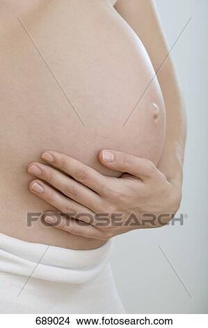 A pregnant woman holding her stomach View Large Photo Image Picture - A pregnant woman holding her stomach. Fotosearch