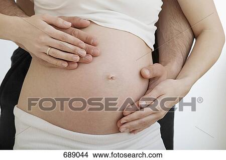 Husband holding pregnant wife's belly View Large Photo Image Picture - Husband holding pregnant wife's belly. Fotosearch