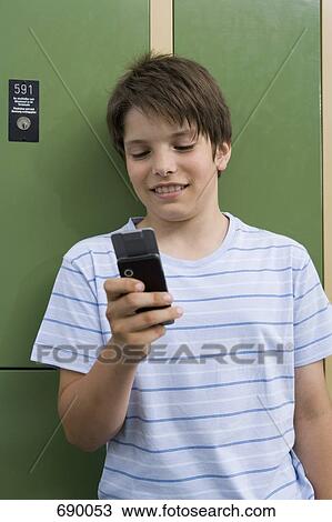 Stock Image - A pre-adolescent boy leaning on lockers text messaging. Fotosearch