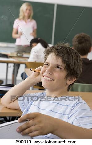 A pre-adolescent boy sitting in the back of a classroom, looking up in contemplation View Large Photo Image Stock Image - A pre-adolescent boy sitting in the back of a classroom, looking up in contemplation. Fotosearch