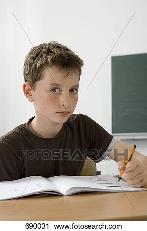 A pre-adolescent boy studying in a classroom View Large Photo Image Stock Image - A pre-adolescent boy studying in a classroom. Fotosearch
