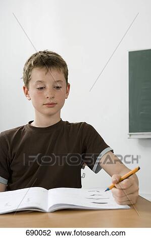 Stock Image - A pre-adolescent boy studying in a classroom. Fotosearch