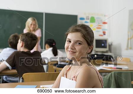 A pre-adolescent girl sitting in the back of a classroom, looking at camera View Large Photo Image Stock Image - A pre-adolescent girl sitting in the back of a classroom, looking at camera. Fotosearch