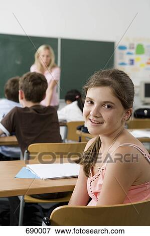 A pre-adolescent girl sitting in the back of a classroom, looking at camera View Large Photo Image Stock Photo - A pre-adolescent girl sitting in the back of a classroom, looking at camera. Fotosearch