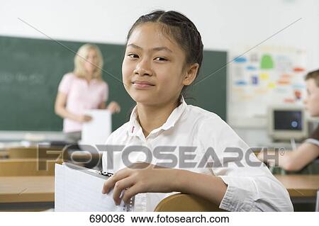 A pre-adolescent girl sitting in the back of a classroom, looking at camera View Large Photo Image Stock Photograph - A pre-adolescent girl sitting in the back of a classroom, looking at camera. Fotosearch