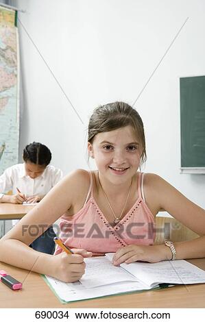 Picture - A pre-adolescent girl studying in a classroom. Fotosearch