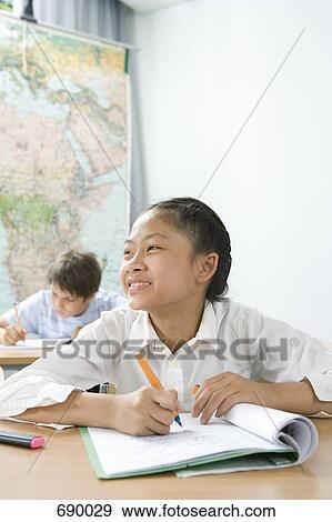 Stock Photo - A pre-adolescent girl studying in a classroom. Fotosearch