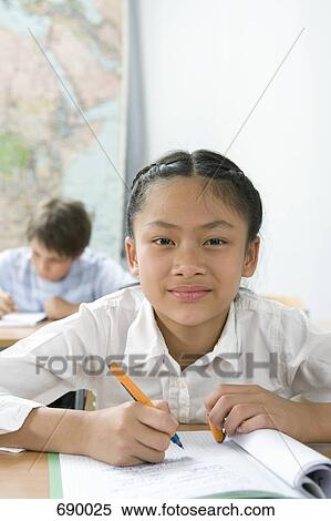 Stock Photography - A pre-adolescent girl studying in a classroom. Fotosearch