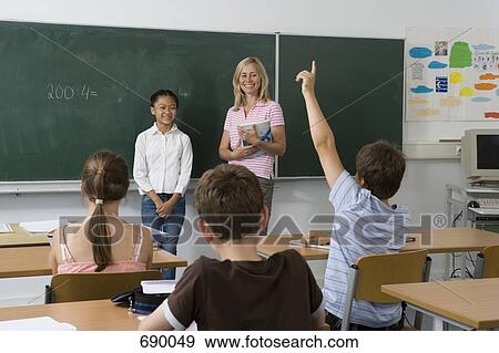 Stock Photo - A teacher and a student at the blackboard, facing the class. Fotosearch