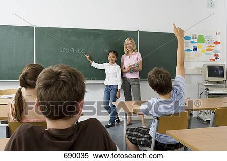 A teacher and a student at the blackboard, facing the class View Large Photo Image Stock Photography - A teacher and a student at the blackboard, facing the class. Fotosearch