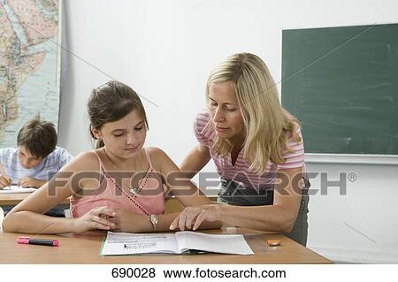Stock Photo - A teacher helping a student in a classroom. Fotosearch
