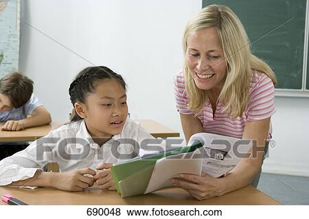 Stock Photo - A teacher helping a student in a classroom. Fotosearch