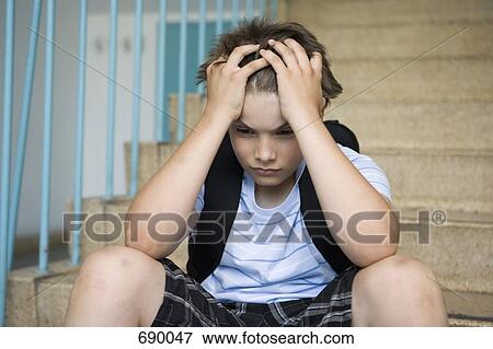 A worried pre-adolescent boy sitting on stairs in a school View Large Photo Image Stock Photo - A worried pre-adolescent boy sitting on stairs in a school. Fotosearch