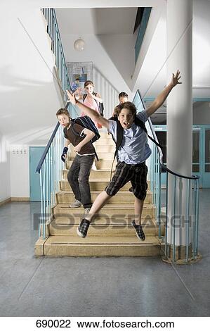 Stock Image - Four pre-adolescent children running down stairs excited. Fotosearch