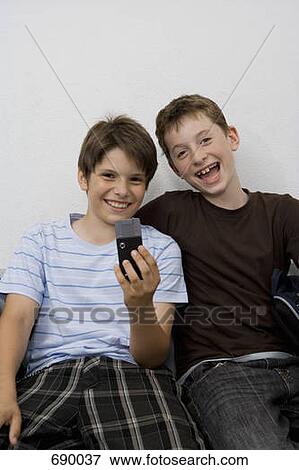 Two pre-adolescent boys looking at a mobile phone View Large Photo Image Stock Photo - Two pre-adolescent boys looking at a mobile phone. Fotosearch