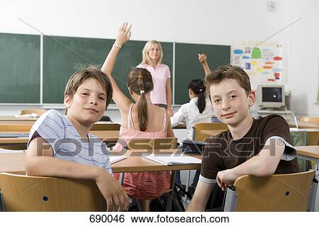 Two pre-adolescent girls sitting in the back of a classroom, looking at camera View Large Photo Image Stock Photograph - Two pre-adolescent girls sitting in the back of a classroom, looking at camera. Fotosearch