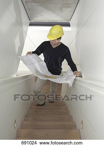 A man standing on a staircase with an architectural drawing View Large Photo Image Picture - A man standing on a staircase with an architectural drawing. Fotosearch