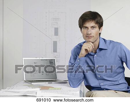 An architect sitting at his desk with a laptop and architectural drawings View Large Photo Image Stock Image - An architect sitting at his desk with a laptop and architectural drawings. Fotosearch