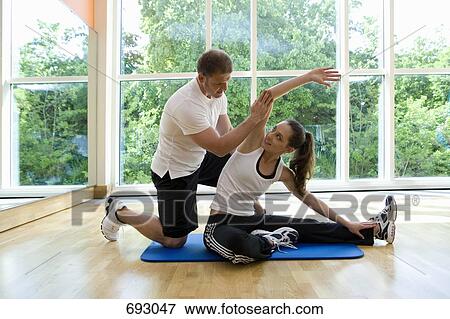 Stock Photo - A fitness instructor helping a young woman stretching. Fotosearch
