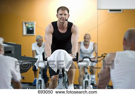 A fitness instructor on a stationary bike teaching a class View Large Photo Image Stock Image - A fitness instructor on a stationary bike teaching a class. Fotosearch
