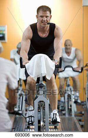 A fitness instructor on a stationary bike teaching a class View Large Photo Image Stock Photograph - A fitness instructor on a stationary bike teaching a class. Fotosearch