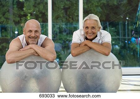 Stock Image - A mature man and a senior woman leaning on exercise balls. Fotosearch