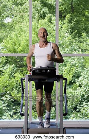Stock Image - A mature man running on a treadmill. Fotosearch