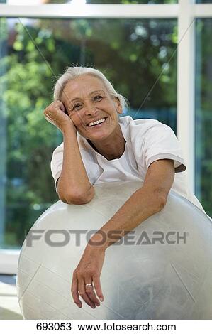 Stock Image - A senior woman leaning on an exercise ball. Fotosearch