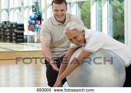 A senior woman on an exercise ball working with a trainer View Large Photo Image Stock Photography - A senior woman on an exercise ball working with a trainer. Fotosearch