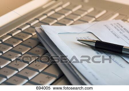 A laptop keyboard with a stack of bills and a pen on it View Large Photo Image Stock Photography - A laptop keyboard with a stack of bills and a pen on it. Fotosearch