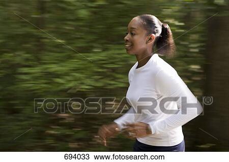 A woman jogging through wooded park View Large Photo Image Stock Image - A woman jogging through wooded park. Fotosearch