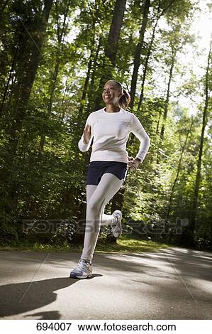 A woman jogging through wooded park View Large Photo Image Stock Photo - A woman jogging through wooded park. Fotosearch
