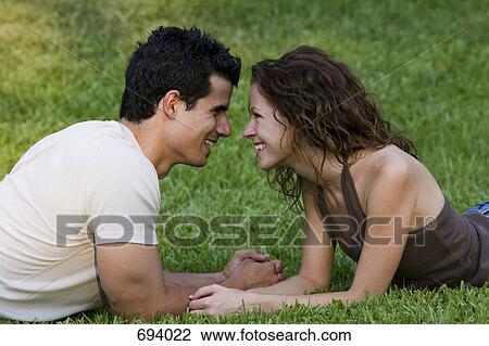 A young couple leaning on their elbows face to face View Large Photo Image Stock Image - A young couple leaning on their elbows face to face. Fotosearch