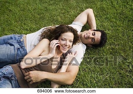 A young couple snuggling on a lawn View Large Photo Image Stock Photograph - A young couple snuggling on a lawn. Fotosearch