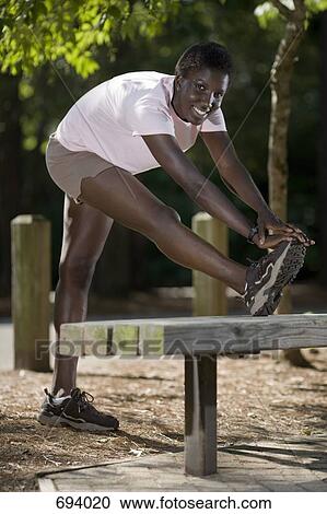 A young woman doing a leg stretch View Large Photo Image Stock Image - A young woman doing a leg stretch. Fotosearch