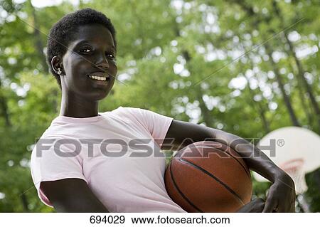 A young woman holding a basketball, outdoors View Large Photo Image Stock Photo - A young woman holding a basketball, outdoors. Fotosearch