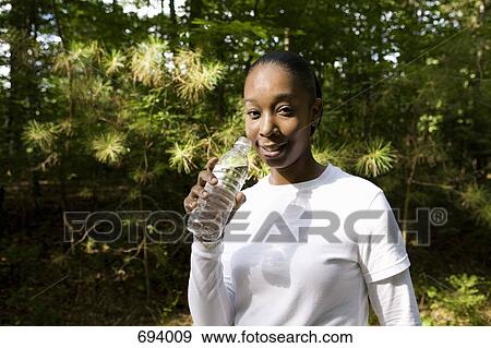 A young woman holding a plastic water bottle, outdoors View Large Photo Image Stock Photo - A young woman holding a plastic water bottle, outdoors. Fotosearch