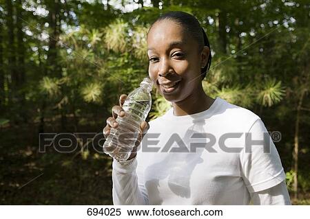A young woman holding a plastic water bottle, outdoors View Large Photo Image Stock Photography - A young woman holding a plastic water bottle, outdoors. Fotosearch