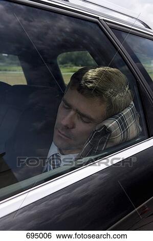 Stock Photograph - A businessman sleeping in a car. Fotosearch